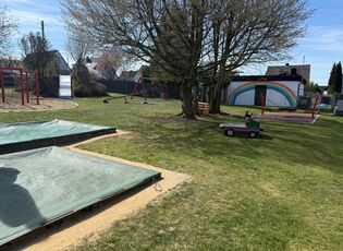 Außengelände mit Wiese, Sandkasten, Schaukel, Klettergerüst und Wippe