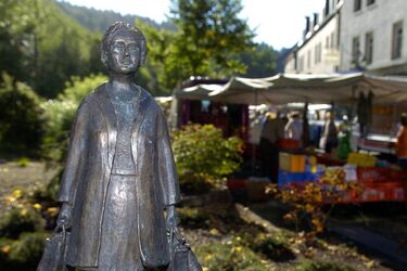 Bronzefigur "Marktfrau" vor emsigen Treiben auf dem Betzdorfer Wochenmarkt
